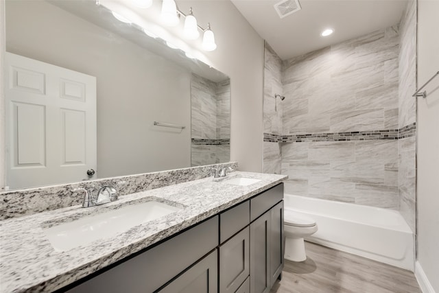 full bathroom featuring tiled shower / bath, hardwood / wood-style flooring, vanity, and toilet