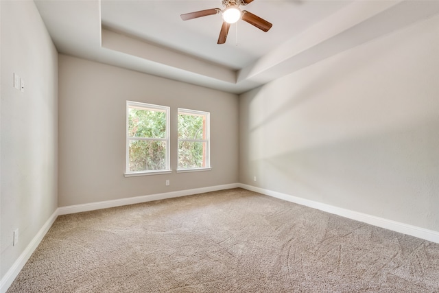 unfurnished room featuring carpet floors, a tray ceiling, and ceiling fan