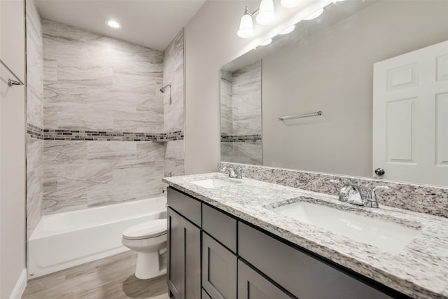 full bathroom featuring wood-type flooring, vanity, tiled shower / bath combo, and toilet