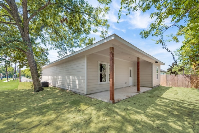 view of side of property with a lawn, a patio, and central AC unit