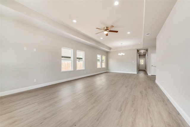 unfurnished living room featuring ceiling fan with notable chandelier and light hardwood / wood-style floors