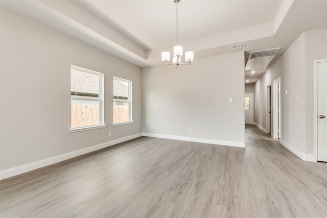 spare room featuring light hardwood / wood-style floors, a tray ceiling, and a notable chandelier