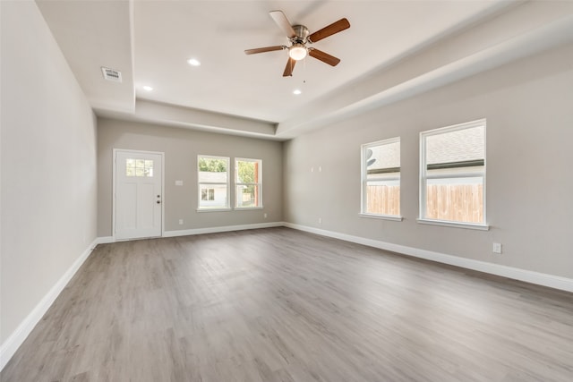 interior space featuring ceiling fan, a tray ceiling, and light hardwood / wood-style floors