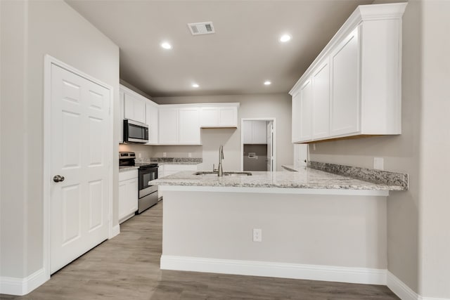 kitchen featuring light wood-type flooring, sink, white cabinets, kitchen peninsula, and appliances with stainless steel finishes