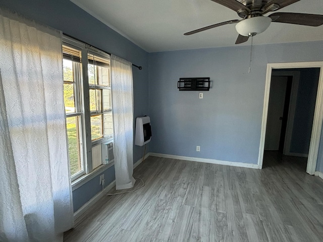 unfurnished room featuring light wood-type flooring, ceiling fan, and heating unit