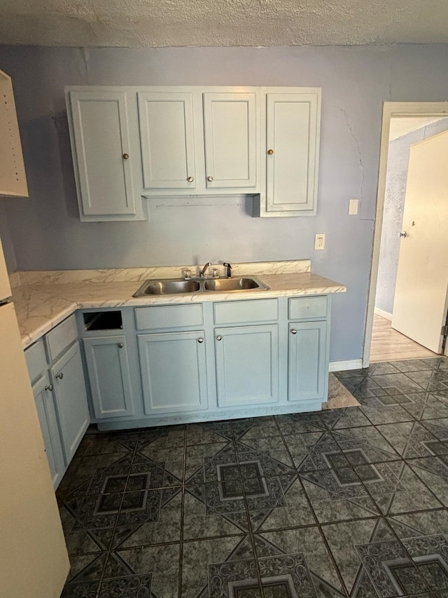 kitchen featuring a textured ceiling, sink, and white cabinets