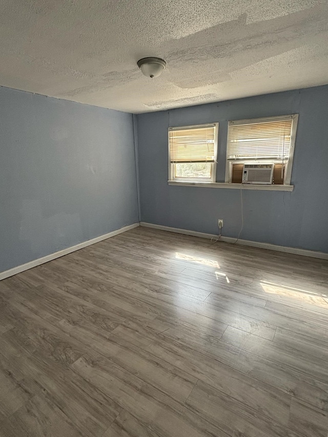 empty room featuring a textured ceiling, wood-type flooring, and cooling unit