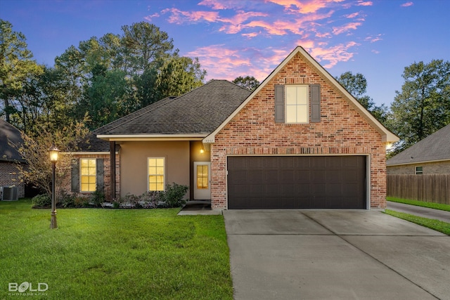 front of property with a lawn, central AC unit, and a garage