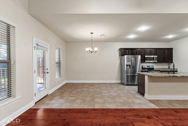 kitchen with light stone counters, sink, appliances with stainless steel finishes, and light hardwood / wood-style flooring