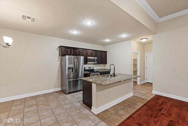 kitchen featuring light stone countertops, sink, crown molding, a center island with sink, and appliances with stainless steel finishes