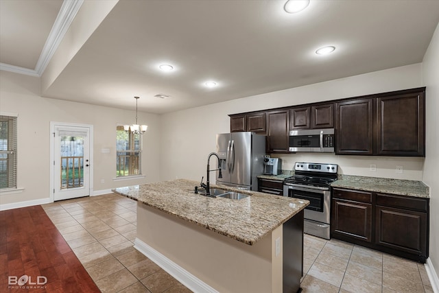 kitchen featuring appliances with stainless steel finishes, ornamental molding, sink, light hardwood / wood-style floors, and an island with sink