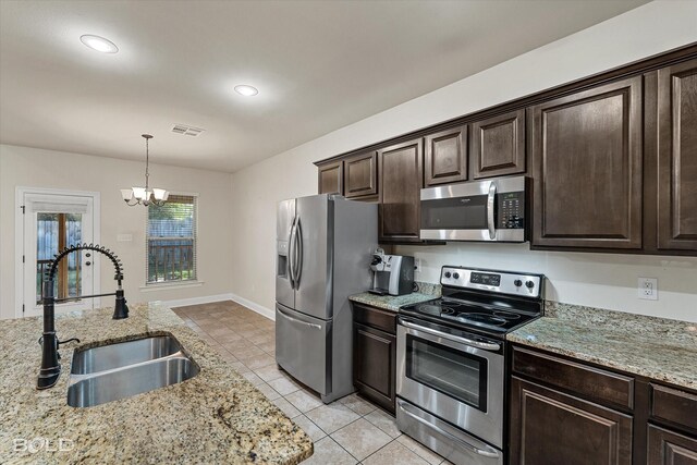 kitchen with sink, light stone countertops, decorative light fixtures, dark brown cabinetry, and stainless steel appliances