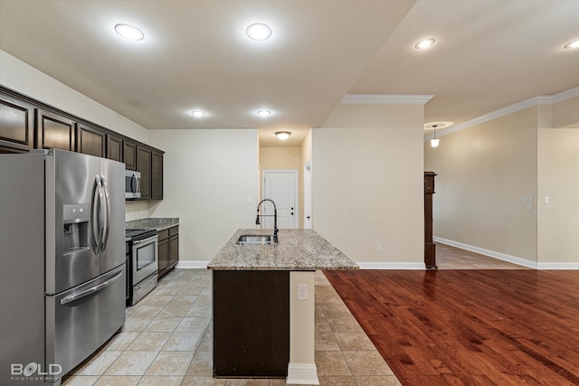 kitchen featuring a center island with sink, sink, light hardwood / wood-style flooring, ornamental molding, and stainless steel appliances