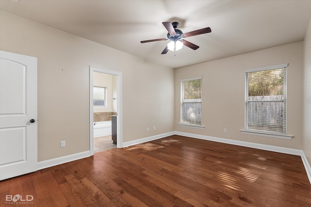 unfurnished bedroom with dark hardwood / wood-style flooring, connected bathroom, and multiple windows