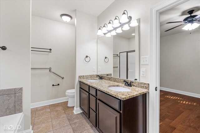 bathroom featuring vanity, a shower with door, ceiling fan, toilet, and wood-type flooring