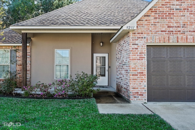 view of exterior entry with a lawn and a garage