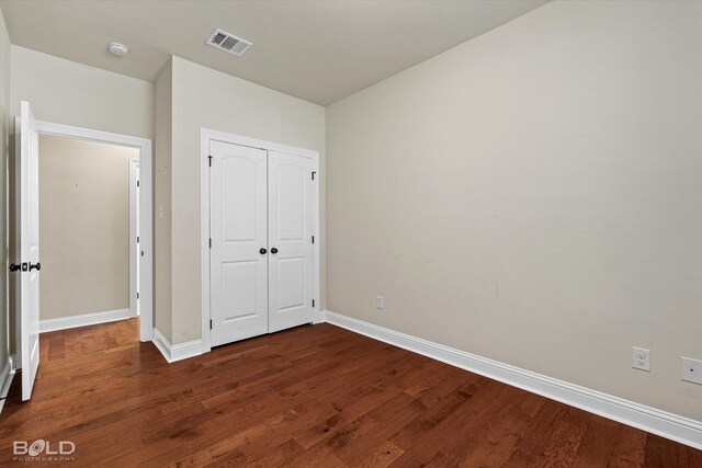 unfurnished bedroom featuring dark wood-type flooring and a closet