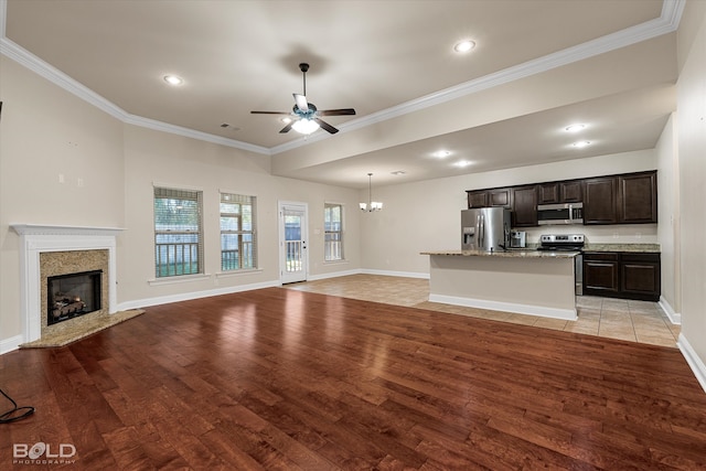 unfurnished living room with ceiling fan with notable chandelier, light hardwood / wood-style flooring, and crown molding