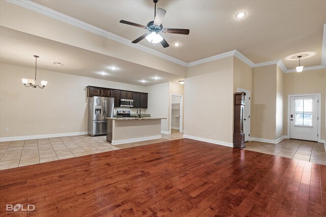 unfurnished living room with sink, ornamental molding, ceiling fan with notable chandelier, and light wood-type flooring