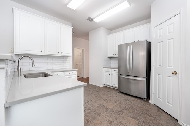 kitchen with white cabinetry, sink, tasteful backsplash, and stainless steel refrigerator