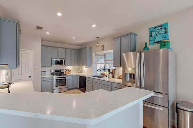 kitchen with pendant lighting, gray cabinets, appliances with stainless steel finishes, and sink