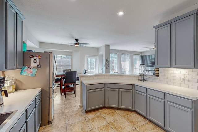 kitchen with kitchen peninsula, ceiling fan, gray cabinets, and tasteful backsplash