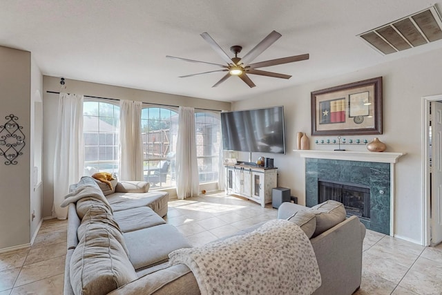 tiled living room with a high end fireplace and ceiling fan