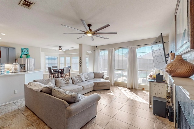 living room with ceiling fan, light tile patterned flooring, and a textured ceiling