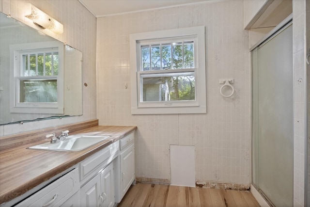 bathroom featuring wood-type flooring, vanity, tile walls, and a shower with door