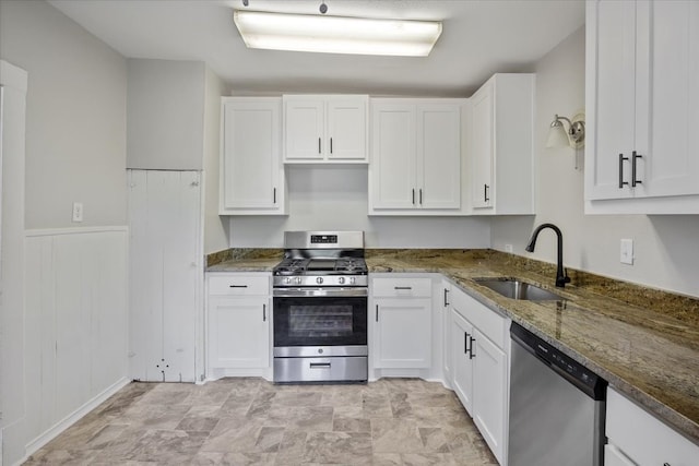 kitchen with dark stone counters, stainless steel appliances, white cabinetry, and sink