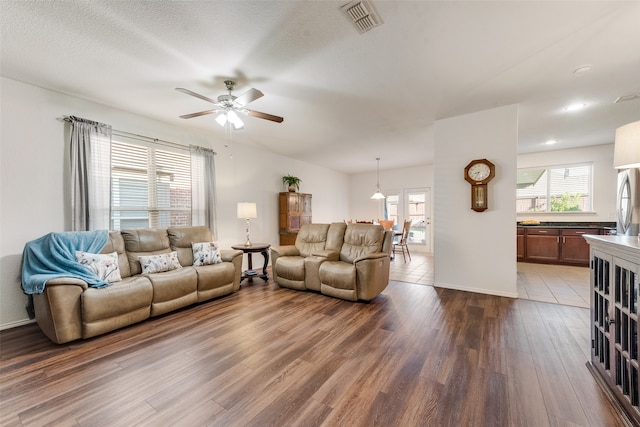 living room with a textured ceiling, wood-type flooring, and ceiling fan