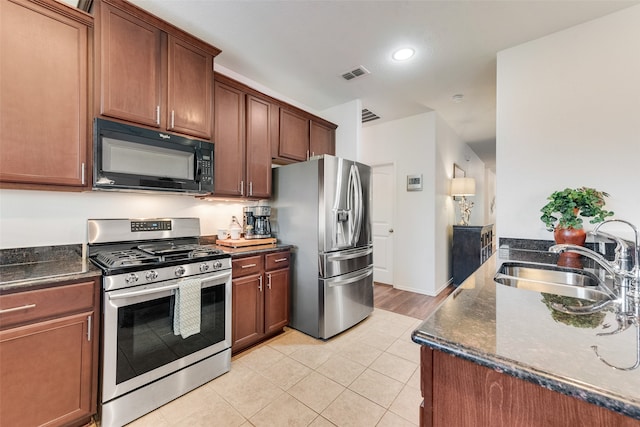 kitchen featuring dark stone countertops, appliances with stainless steel finishes, sink, and light tile patterned flooring