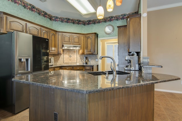 kitchen featuring an island with sink, sink, stainless steel fridge, and backsplash