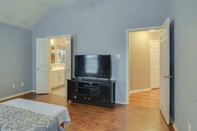 bedroom with wood-type flooring, lofted ceiling, sink, and ensuite bath