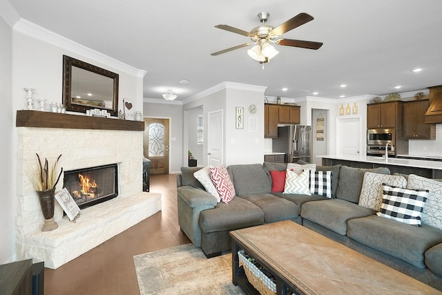 living room featuring a stone fireplace, crown molding, and light hardwood / wood-style flooring