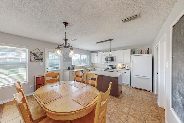 dining room with sink, light tile patterned flooring, and a textured ceiling