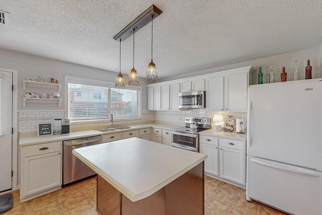 kitchen with a textured ceiling, decorative light fixtures, decorative backsplash, white cabinets, and appliances with stainless steel finishes