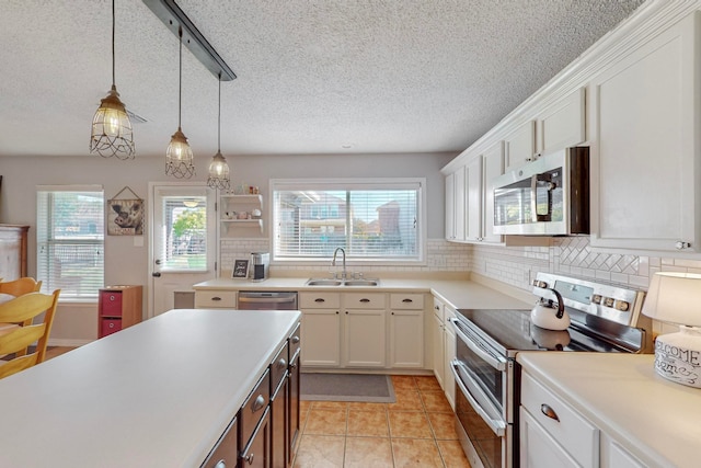 kitchen featuring sink, white cabinets, decorative light fixtures, decorative backsplash, and appliances with stainless steel finishes