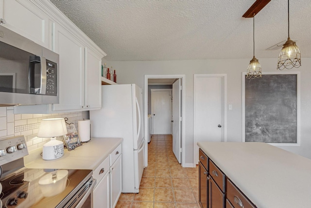 kitchen with appliances with stainless steel finishes, hanging light fixtures, white cabinets, light tile patterned flooring, and decorative backsplash