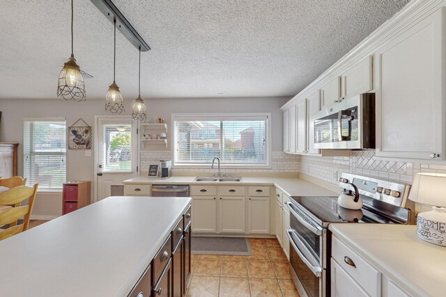 kitchen with sink, decorative light fixtures, white cabinetry, a center island, and appliances with stainless steel finishes