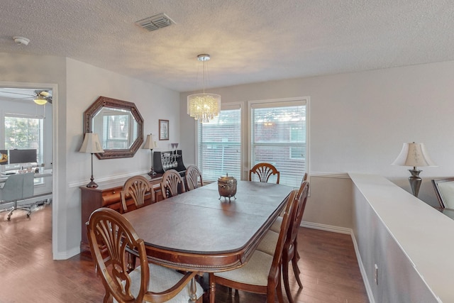 dining room featuring hardwood / wood-style flooring, plenty of natural light, ceiling fan with notable chandelier, and a textured ceiling