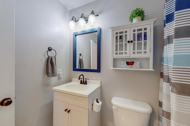 bathroom with toilet, curtained shower, and vanity