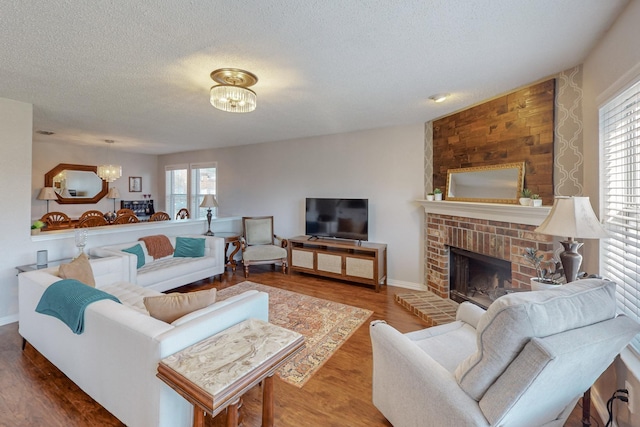 living room featuring a healthy amount of sunlight, a fireplace, a chandelier, and wood-type flooring