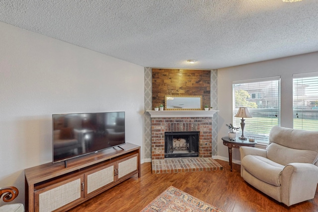 living room with a textured ceiling, a fireplace, and wood-type flooring