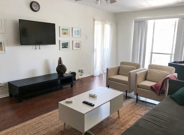 living room with dark wood-type flooring, ceiling fan, and a healthy amount of sunlight