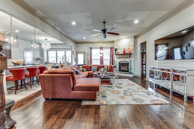 living room featuring a fireplace, ornamental molding, ceiling fan, and dark wood-type flooring