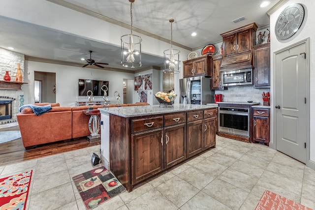 kitchen with a fireplace, hanging light fixtures, a center island, stainless steel appliances, and dark brown cabinets