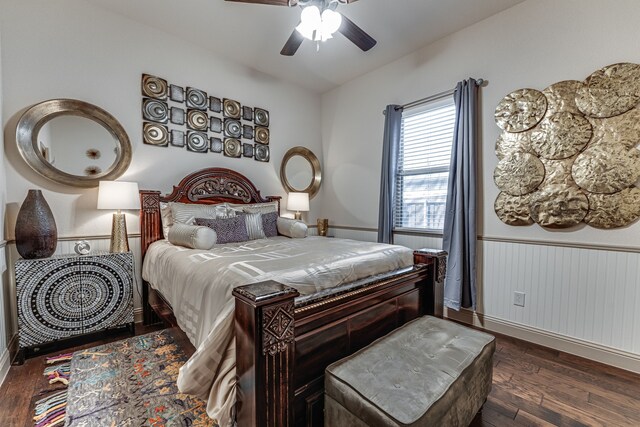 bedroom with wood finished floors, a ceiling fan, baseboards, and wainscoting