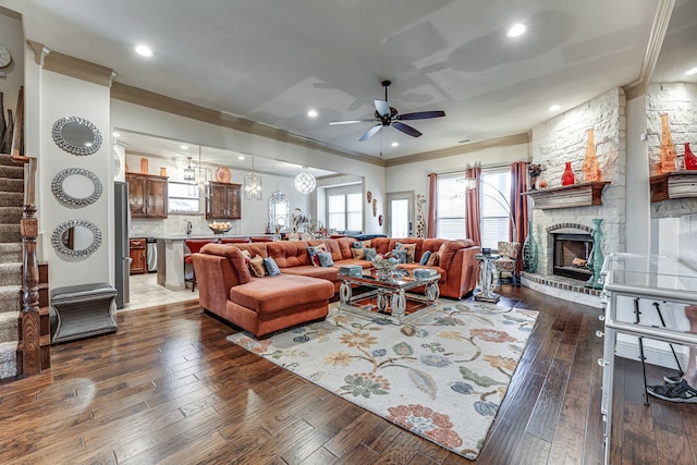 living room featuring dark hardwood / wood-style flooring, a stone fireplace, ceiling fan, and sink