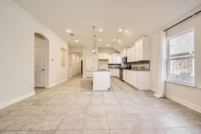 kitchen with sink, stainless steel appliances, pendant lighting, vaulted ceiling, and a kitchen island with sink